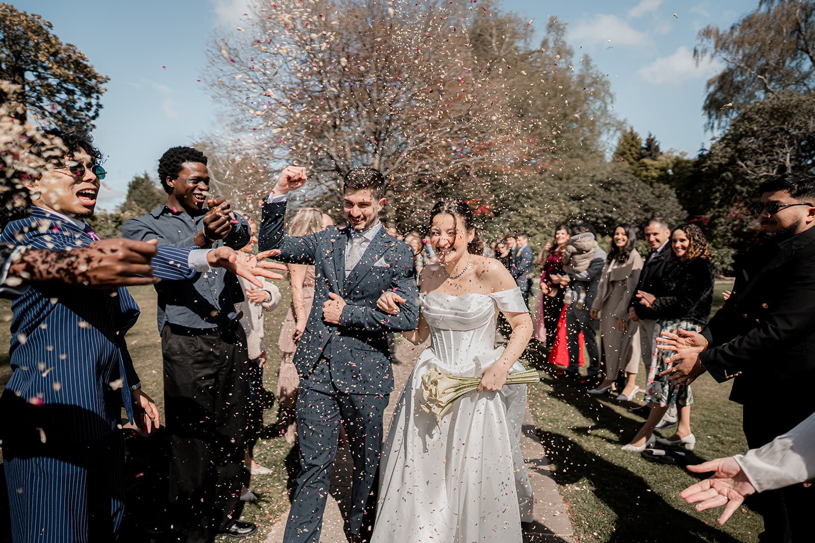 Guests throwing confetti as the couple walk the path at Highley Manor