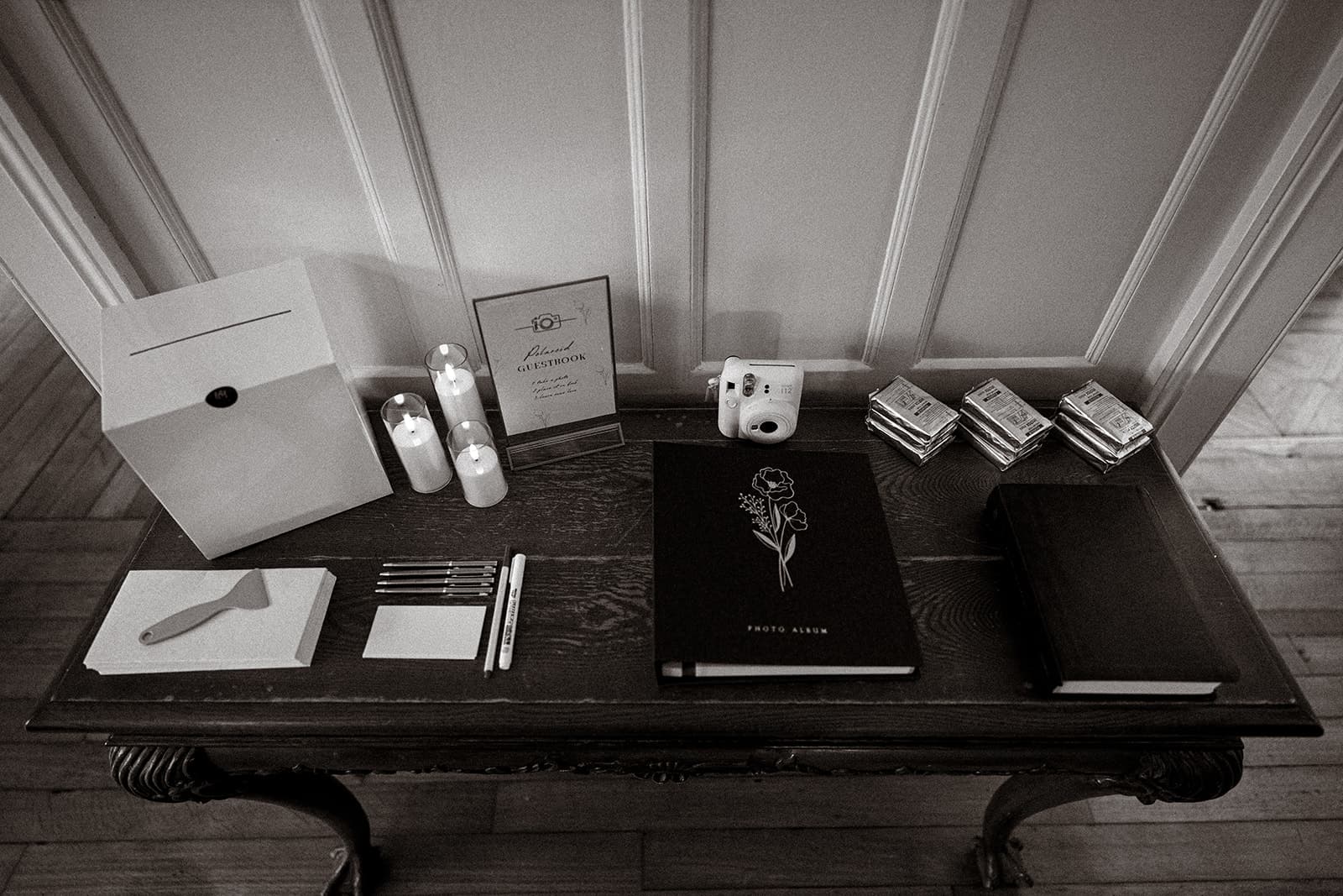 Welcome table with photo album and instant-camera guestbook at Highley Manor
