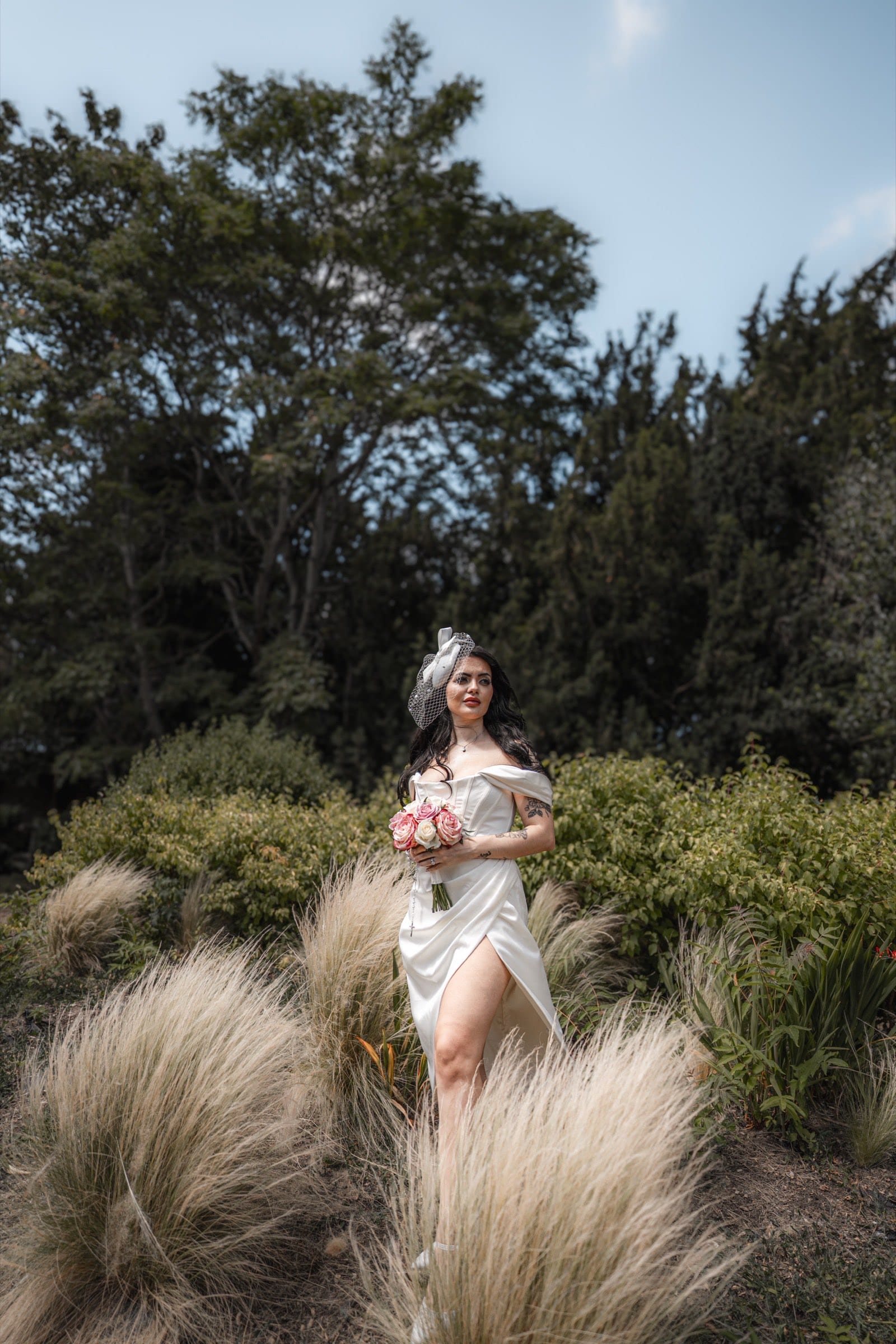 A bride with her bouquet in a garden after her wedding ceremony