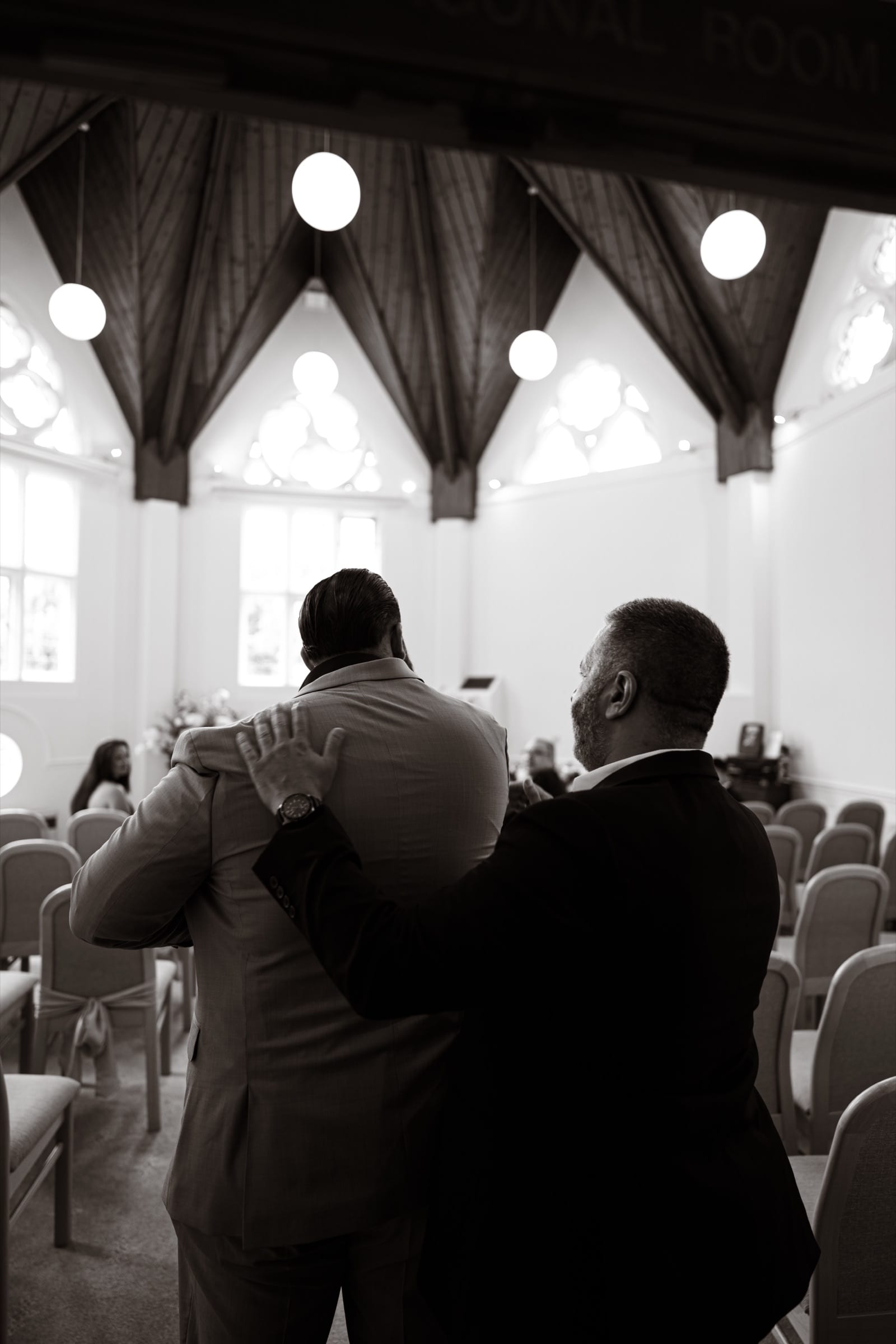 Two men embracing in the ceremony room before a London register office wedding