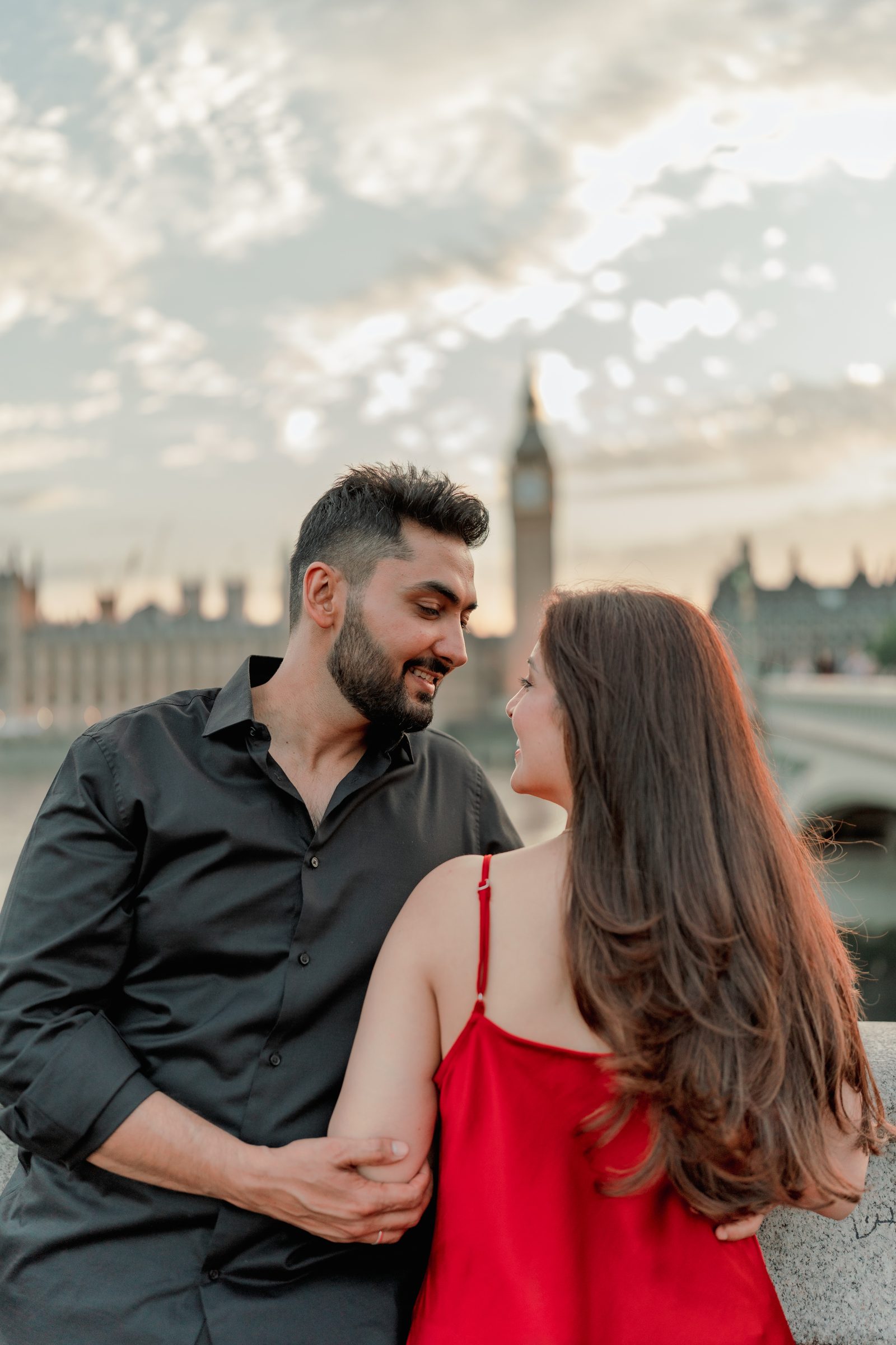A close portrait of Prachi and Rohit at sunset by the Thames, warm light on their faces, Big Ben soft in the distance