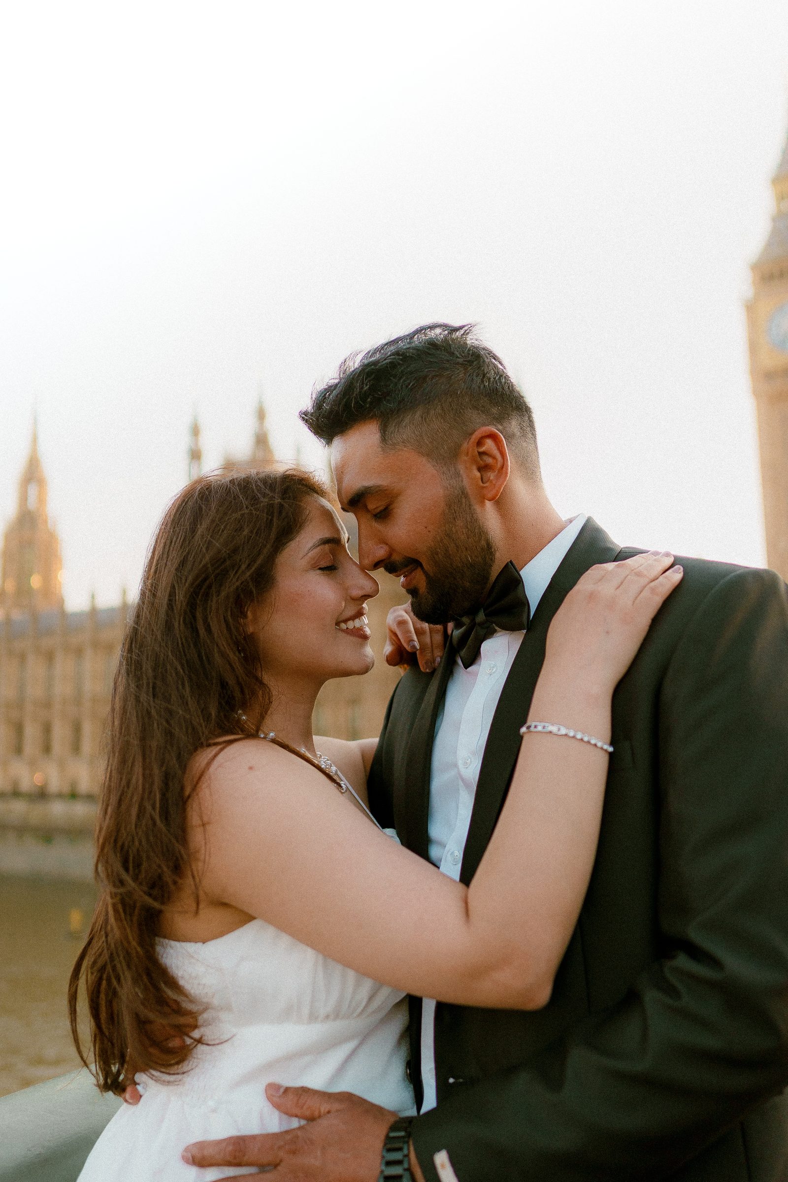A couple close to kissing on Westminster Bridge at golden hour, Big Ben glowing gold behind them