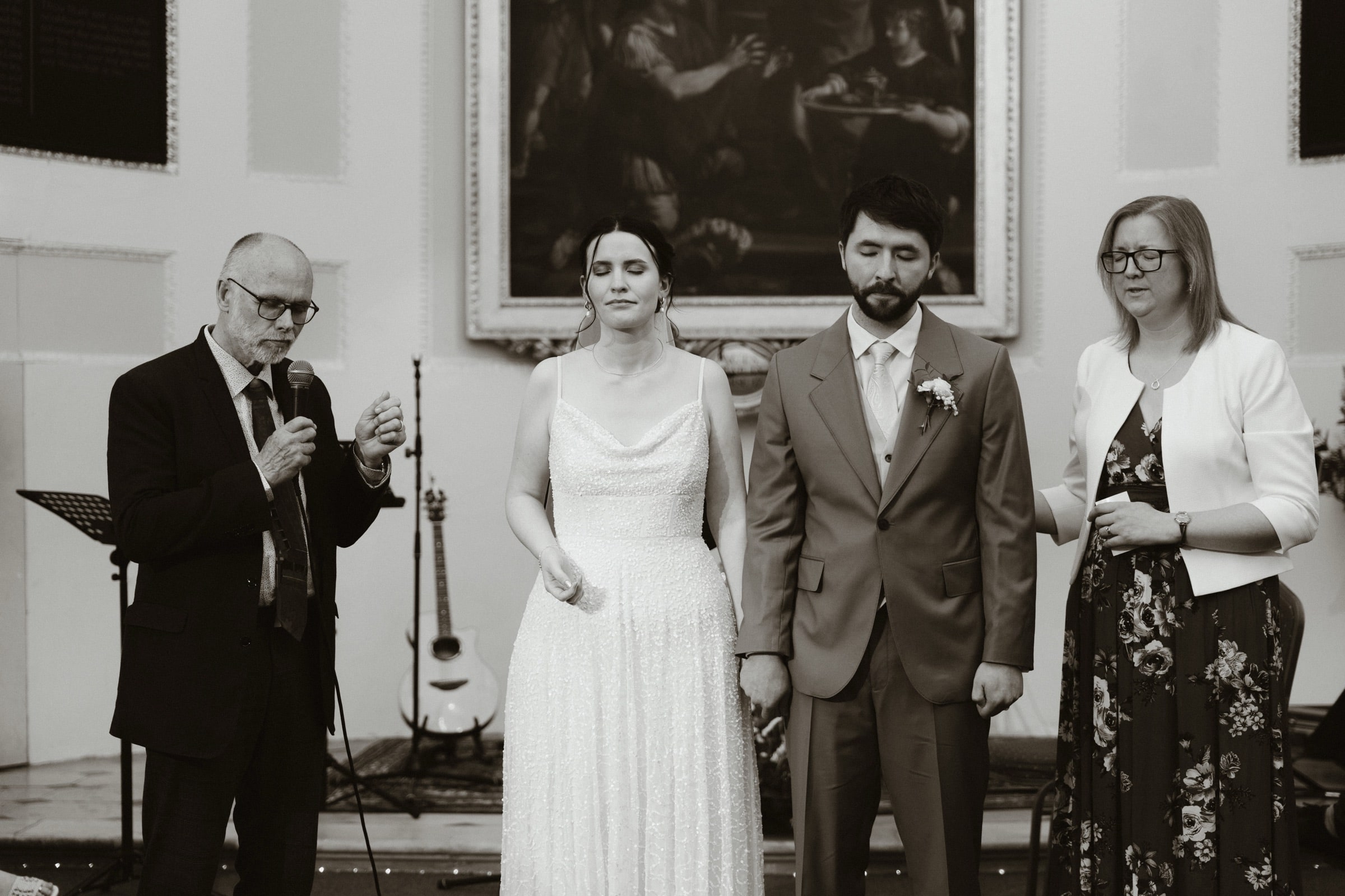 Black and white photograph of the couple and their parents during a blessing beneath the apse at All Hallows-on-the-Wall, City of London