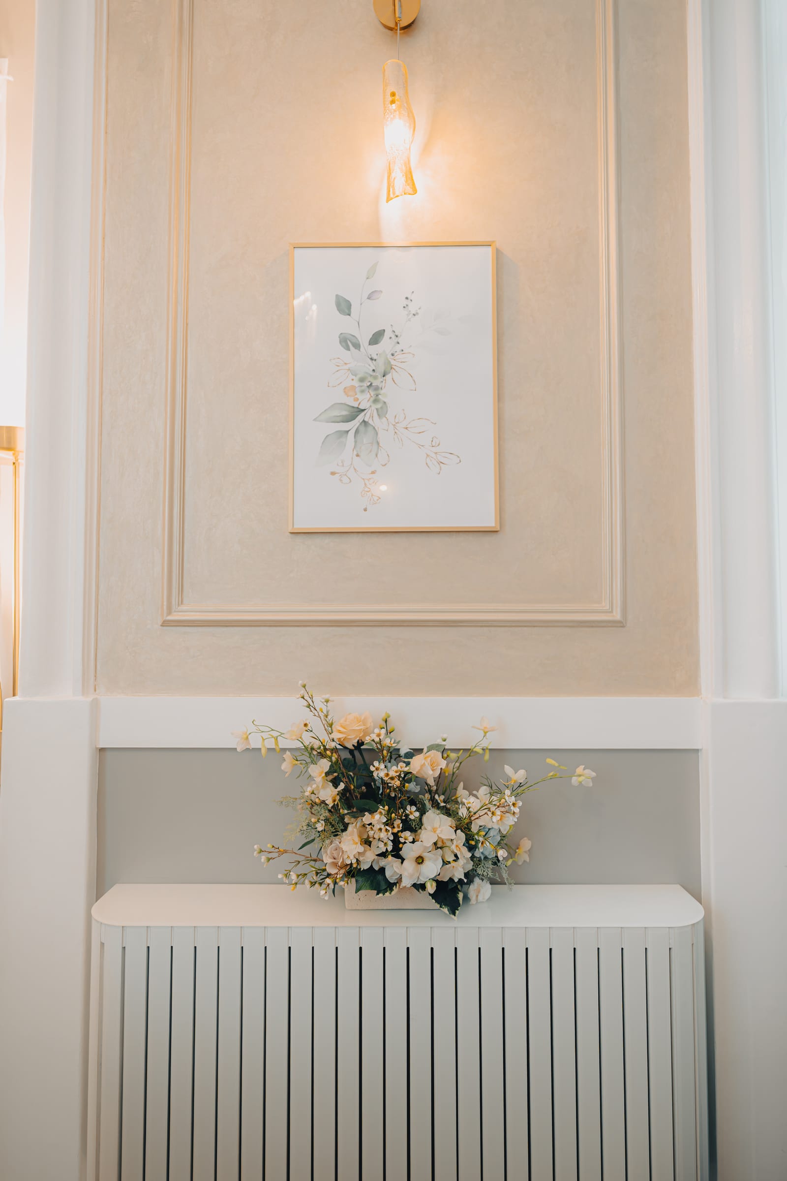 A framed botanical print and floral arrangement on the panelled wall of a ceremony room at Chelsea Old Town Hall
