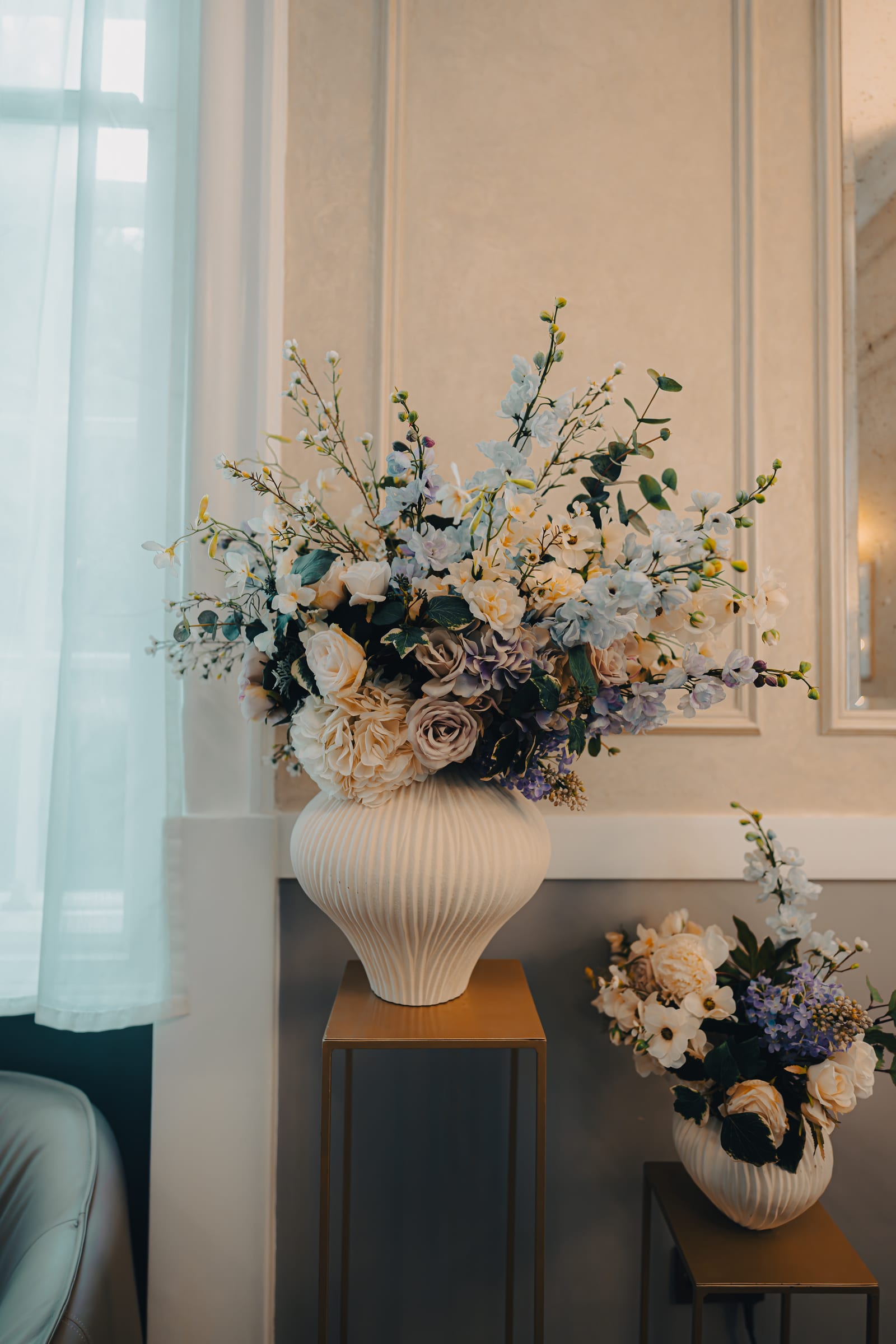 A tall floral arrangement on a console table against the panelled wall of a Chelsea Old Town Hall ceremony room