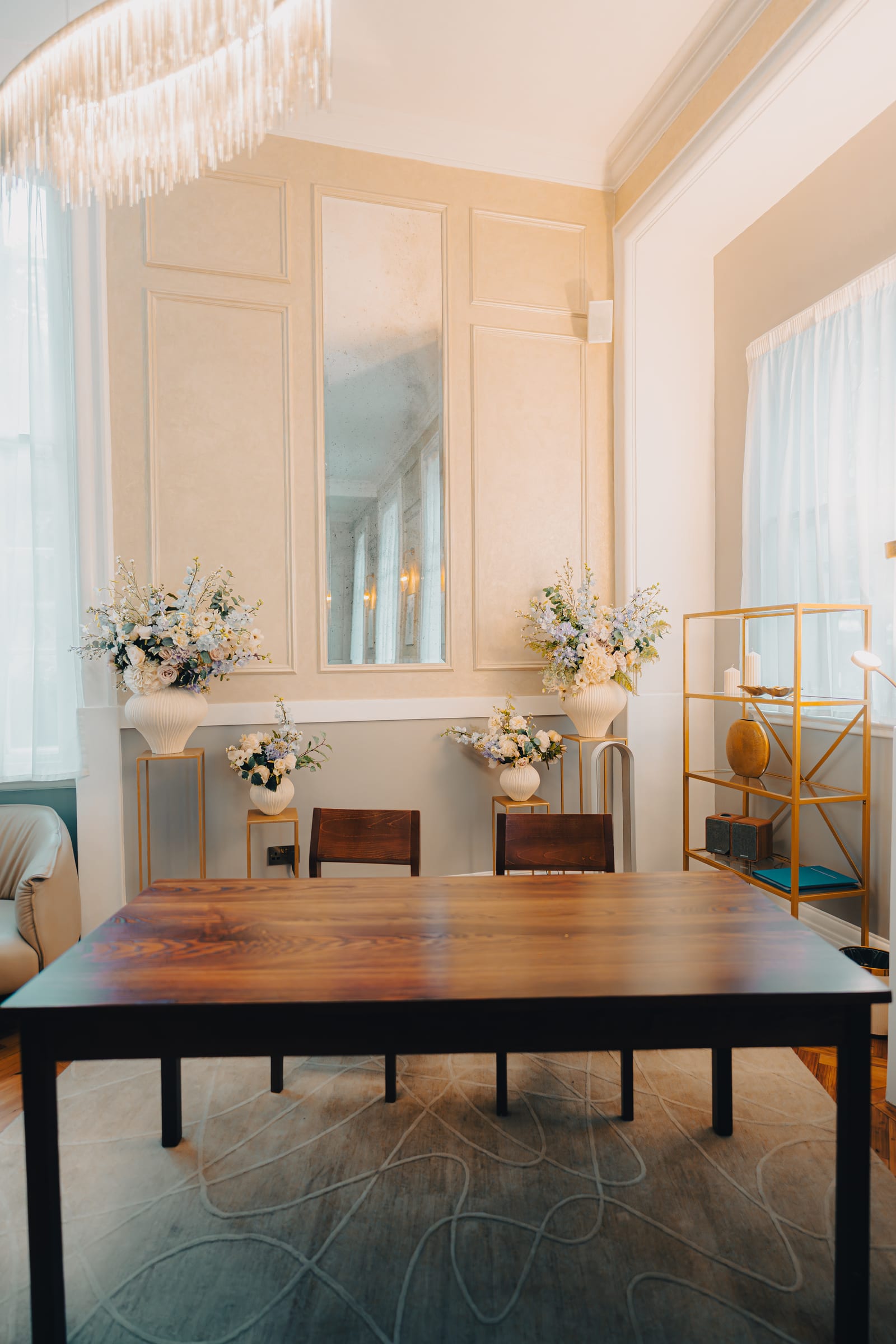 A panelled ceremony room at Chelsea Old Town Hall set with flowers, a chandelier and tall sash windows