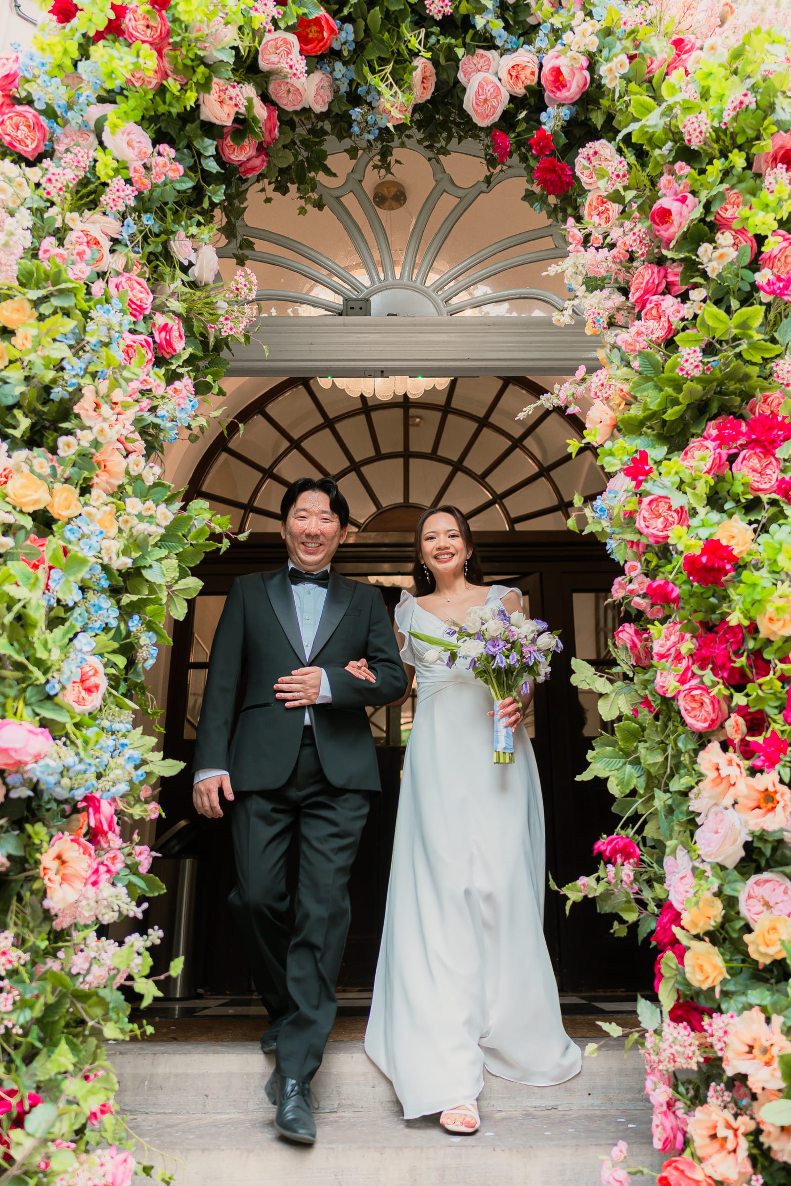 The couple showered in petal confetti at the top of the steps beneath the floral arch at Chelsea Old Town Hall
