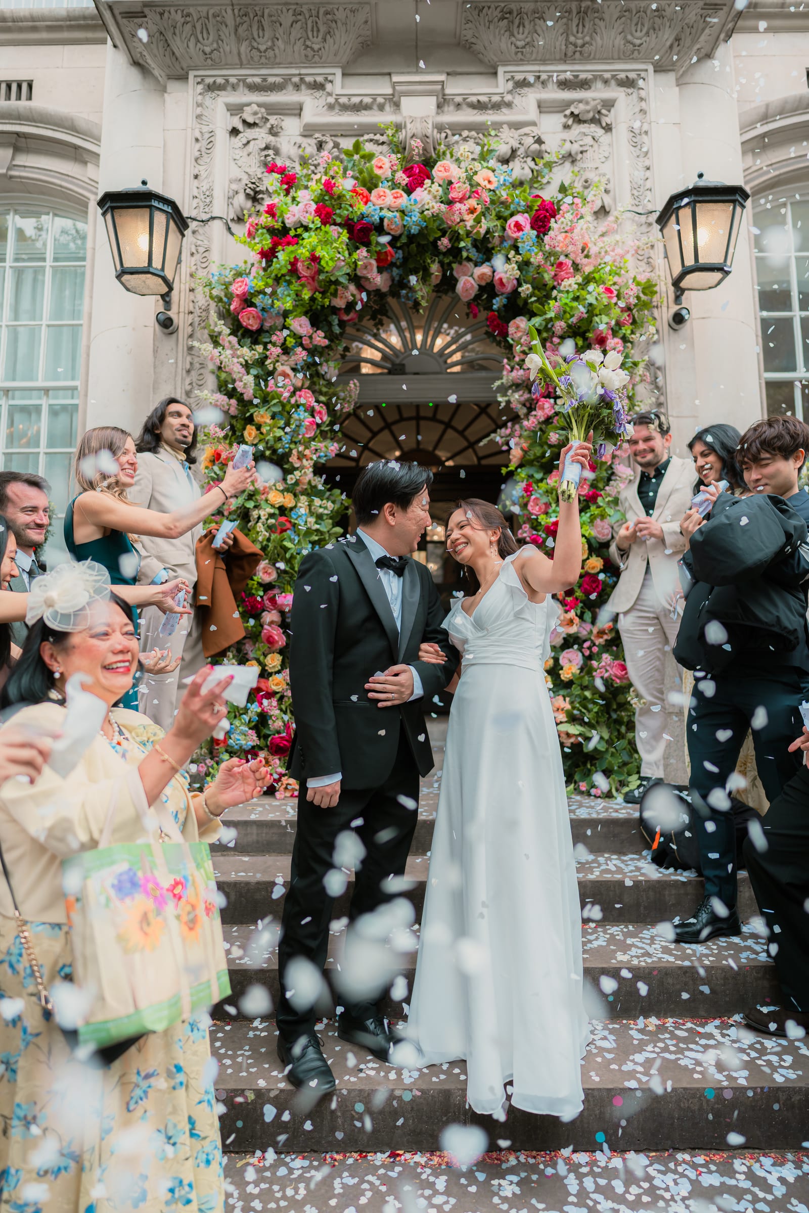 Petal confetti filling the air as the couple come down the front steps of Chelsea Old Town Hall