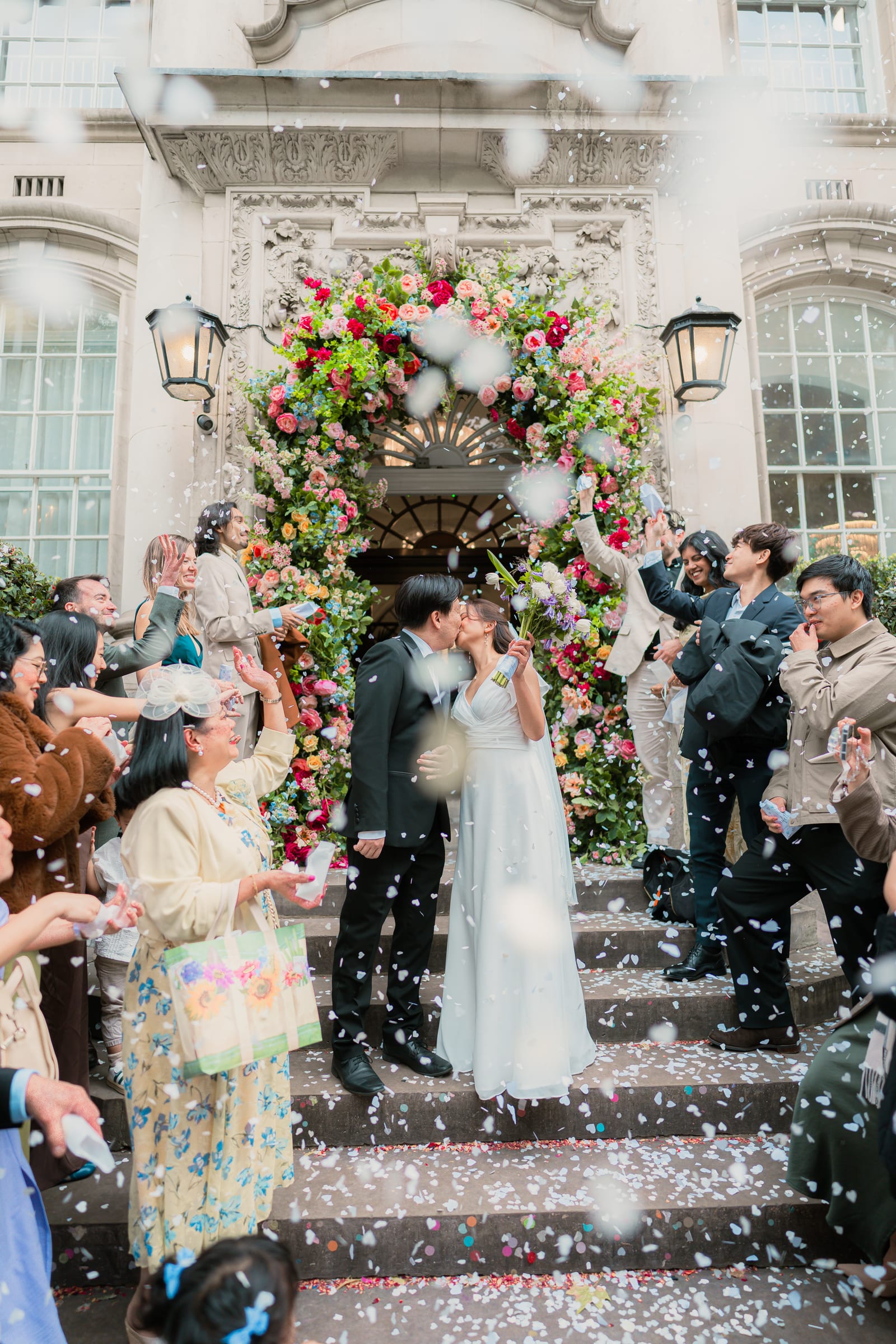 Bride and groom walking down the front steps of Chelsea Old Town Hall through a shower of petal confetti