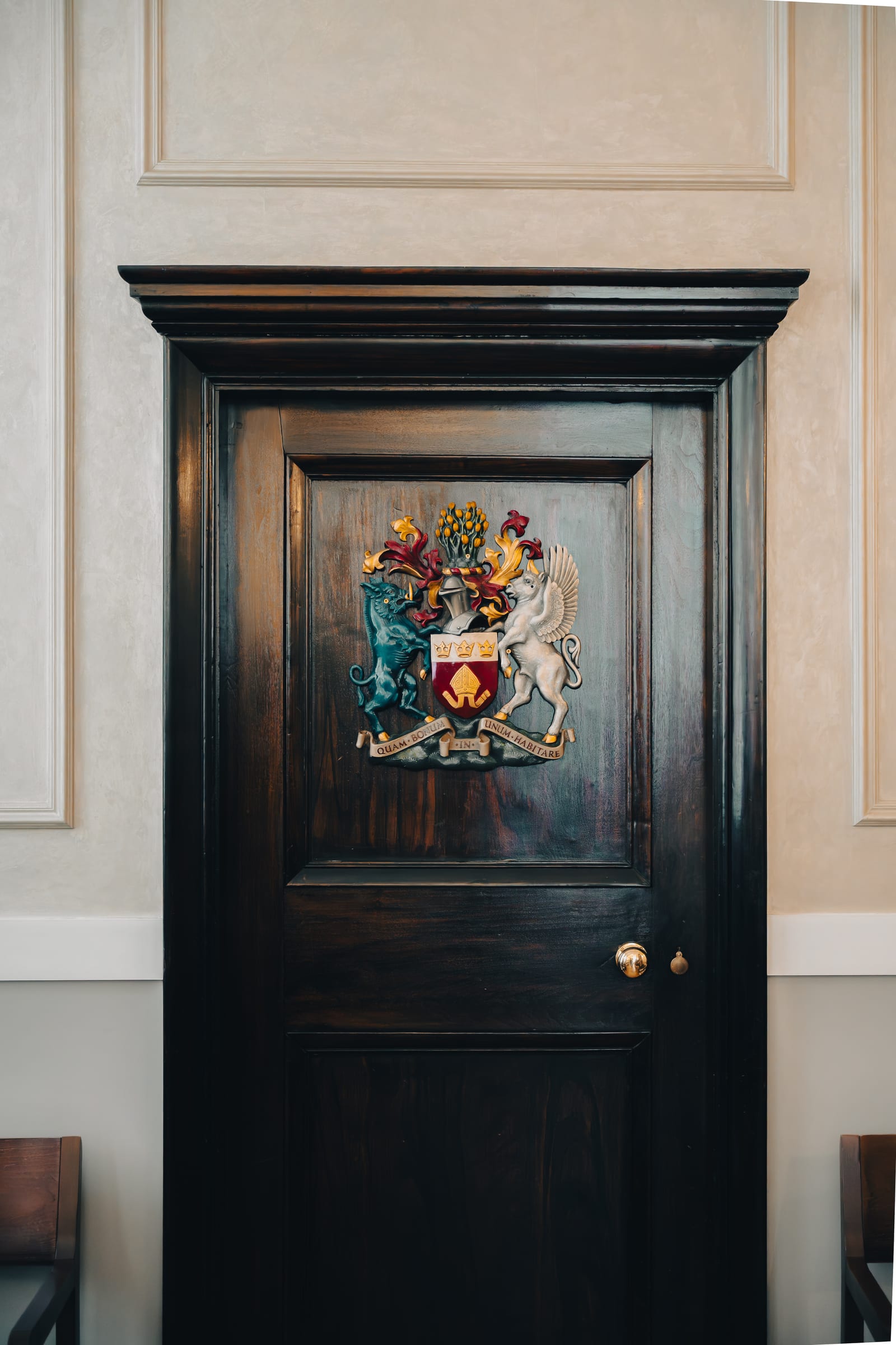A painted heraldic crest on a dark panelled door inside Chelsea Old Town Hall