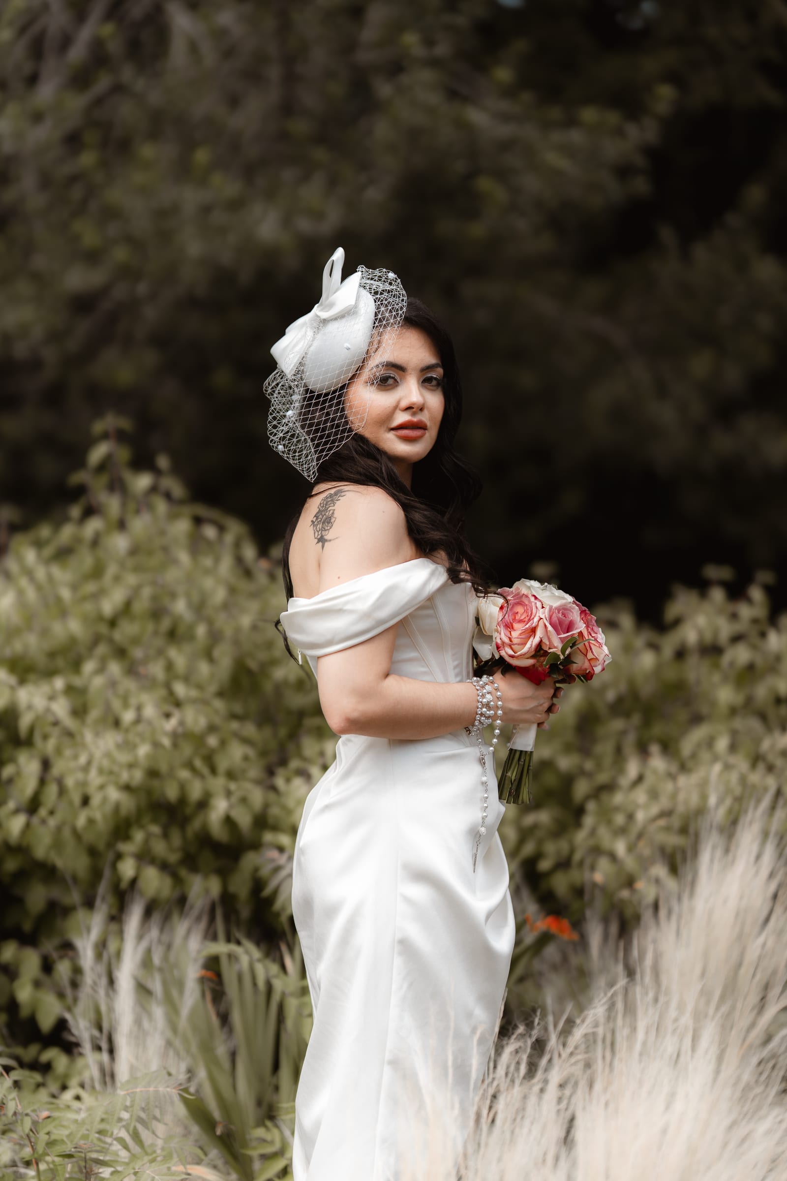 A bride glancing back over her shoulder in the garden borders at Cheshunt Register Office