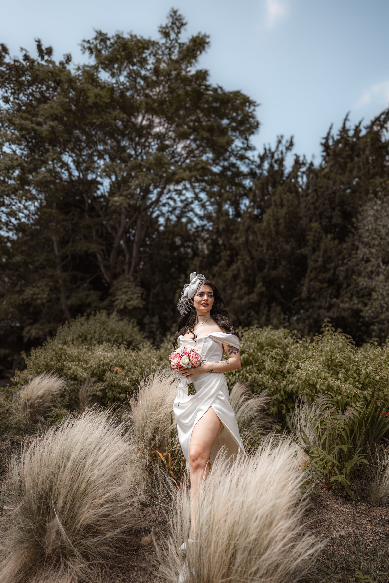 A bride standing among tall ornamental grasses in the grounds of Cheshunt Register Office