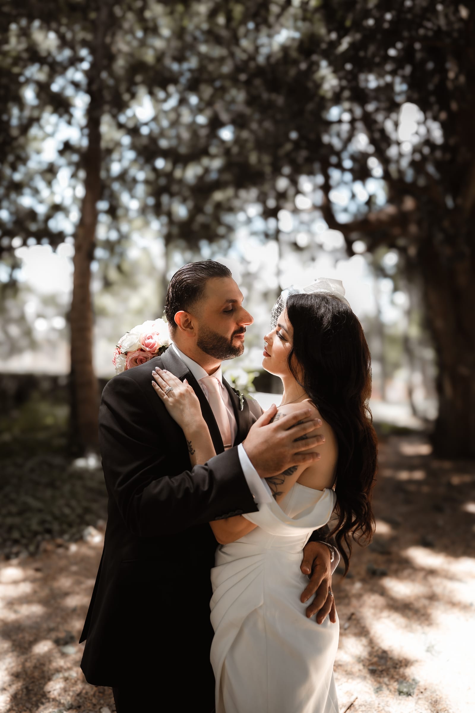 A couple standing close together under the trees in the grounds of Cheshunt Register Office after their wedding