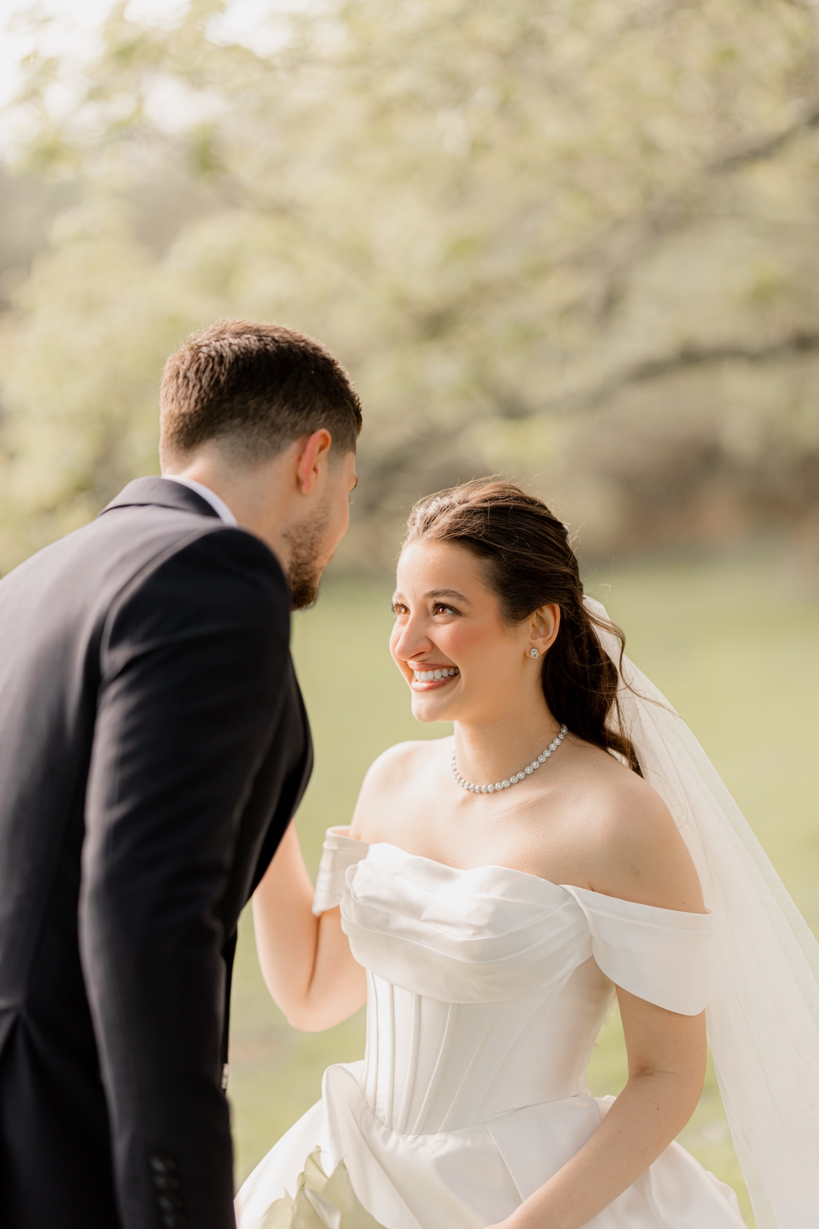 Bride laughing with her groom among spring blossom trees at Highley Manor
