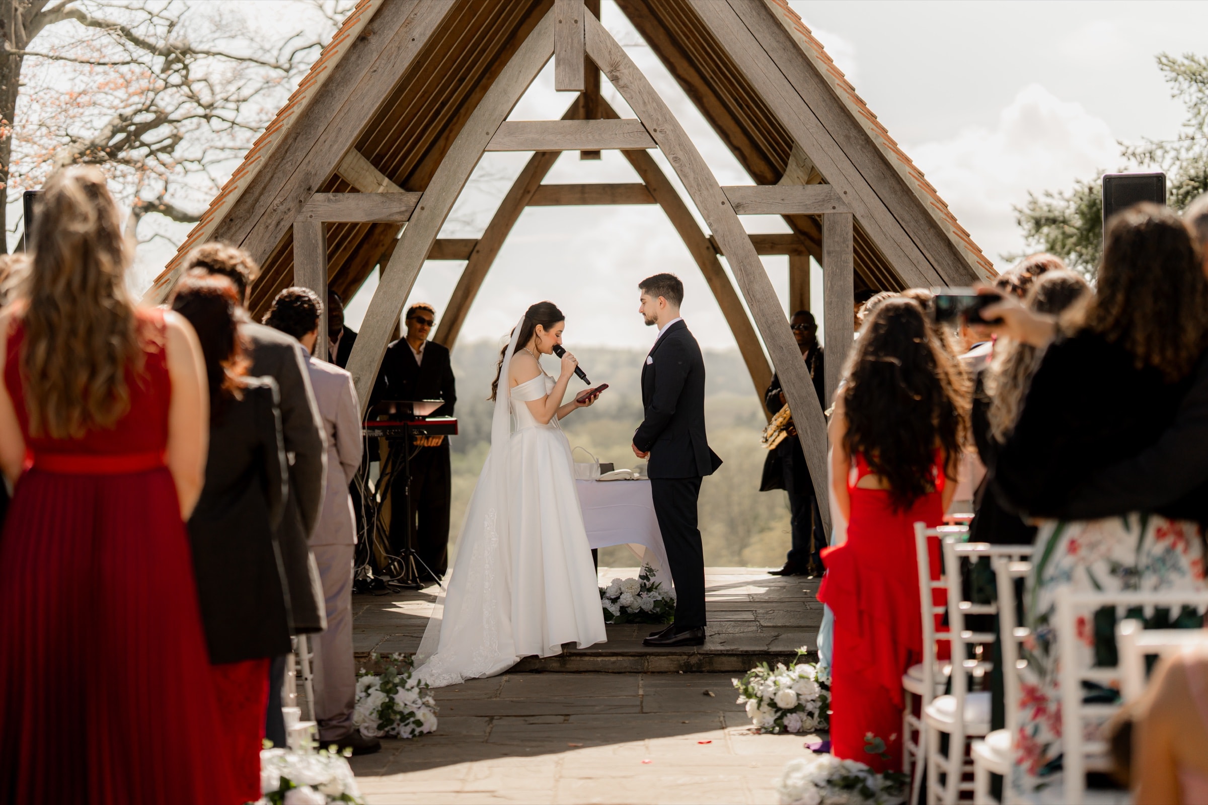 Bride and groom exchanging vows under the oak A-frame glass pavilion at Highley Manor overlooking the South Downs
