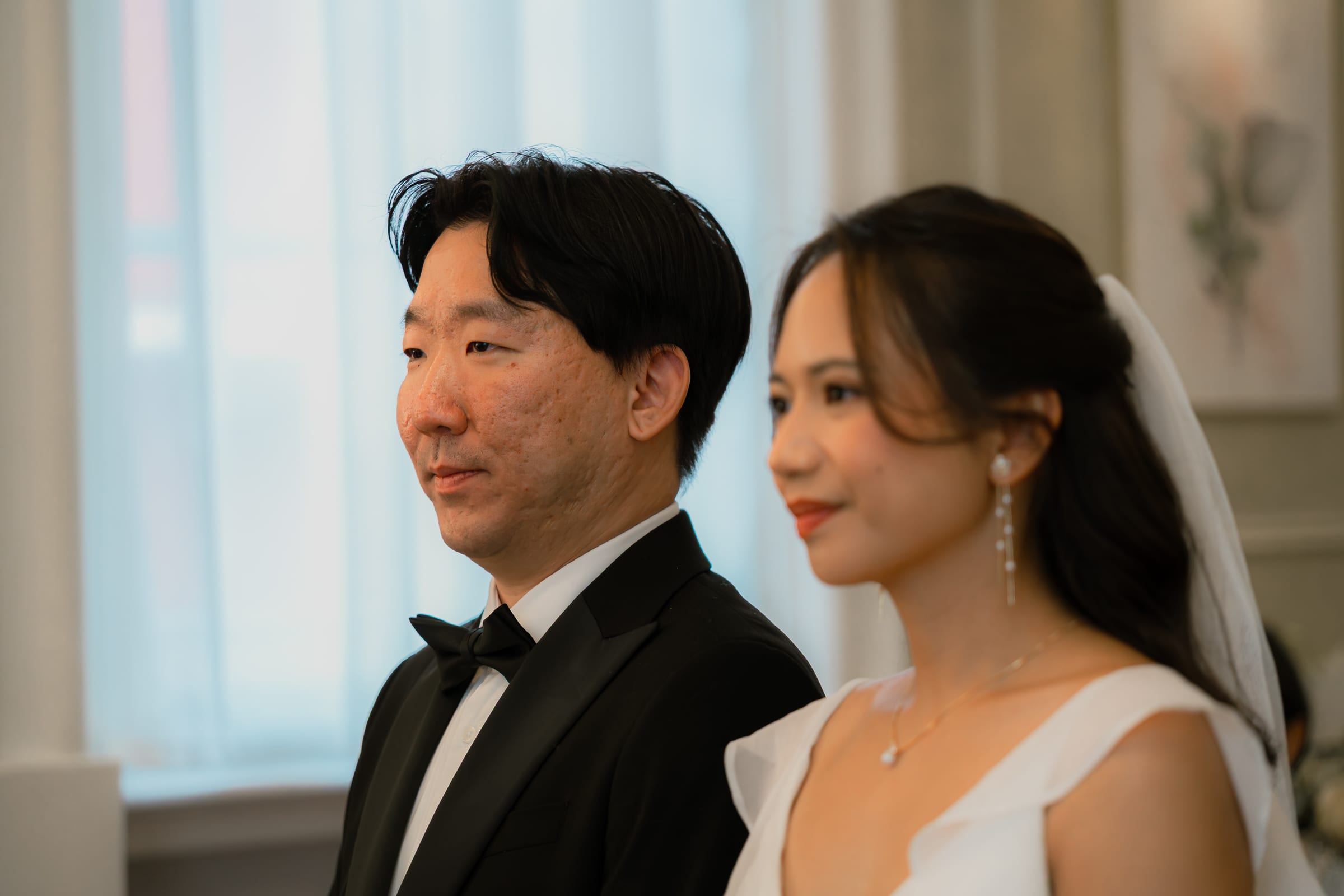 A couple side by side during their civil wedding vows in a panelled London room