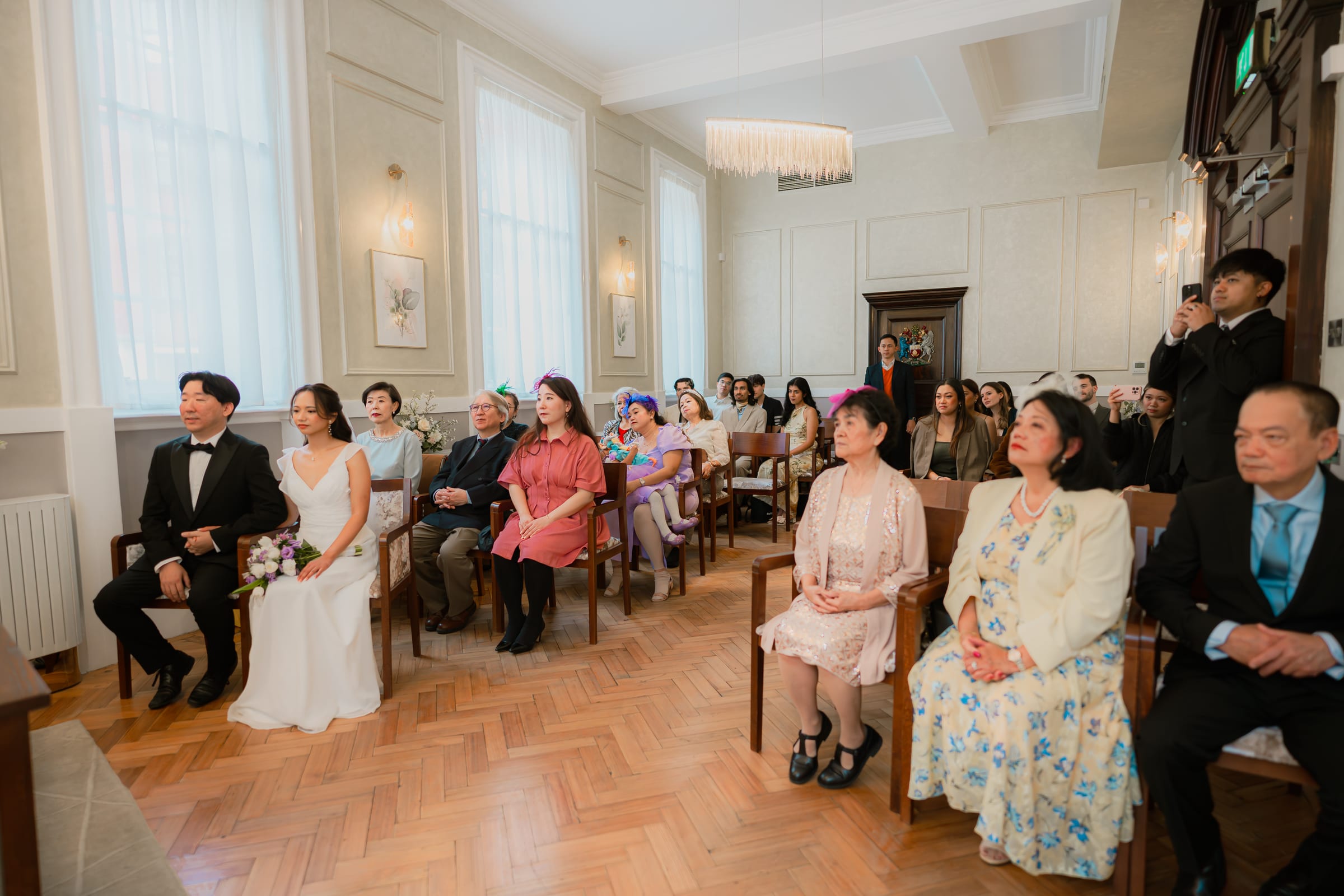 Guests seated in a panelled ceremony room at a London register office