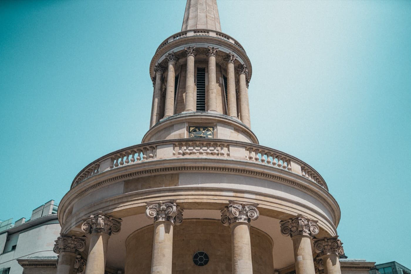 The round colonnade and needle spire of All Souls, Langham Place, against a blue sky