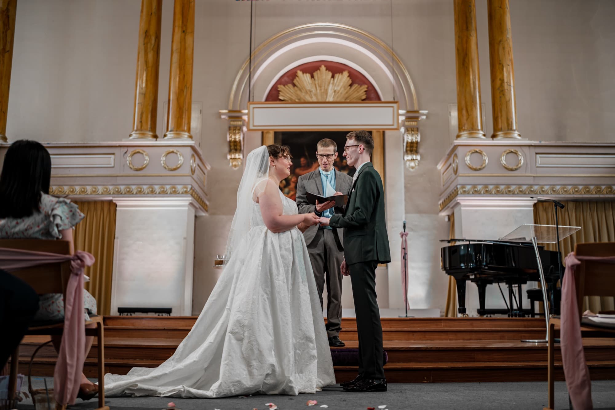 Bride and groom holding hands during their wedding ceremony at the front of All Souls, Langham Place