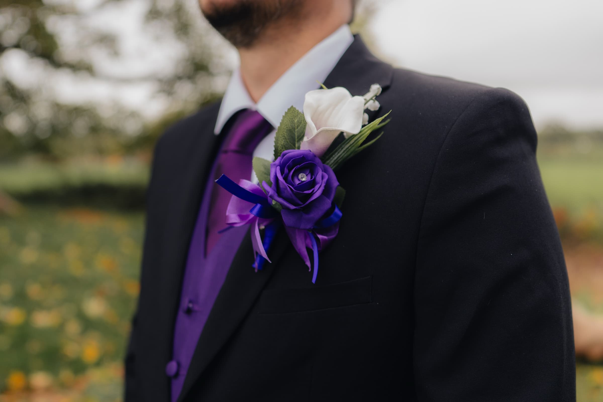 Close-up of a purple rose buttonhole on the groom’s suit at Ashton Lodge Country House