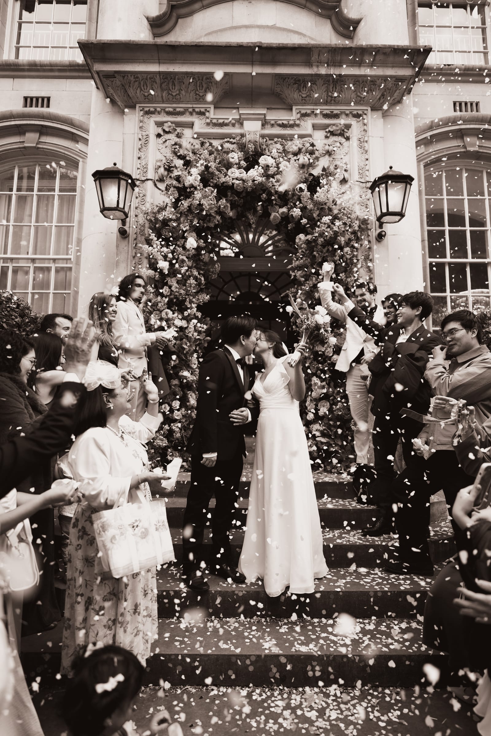 A couple laughing through a confetti throw on the steps of a London town hall