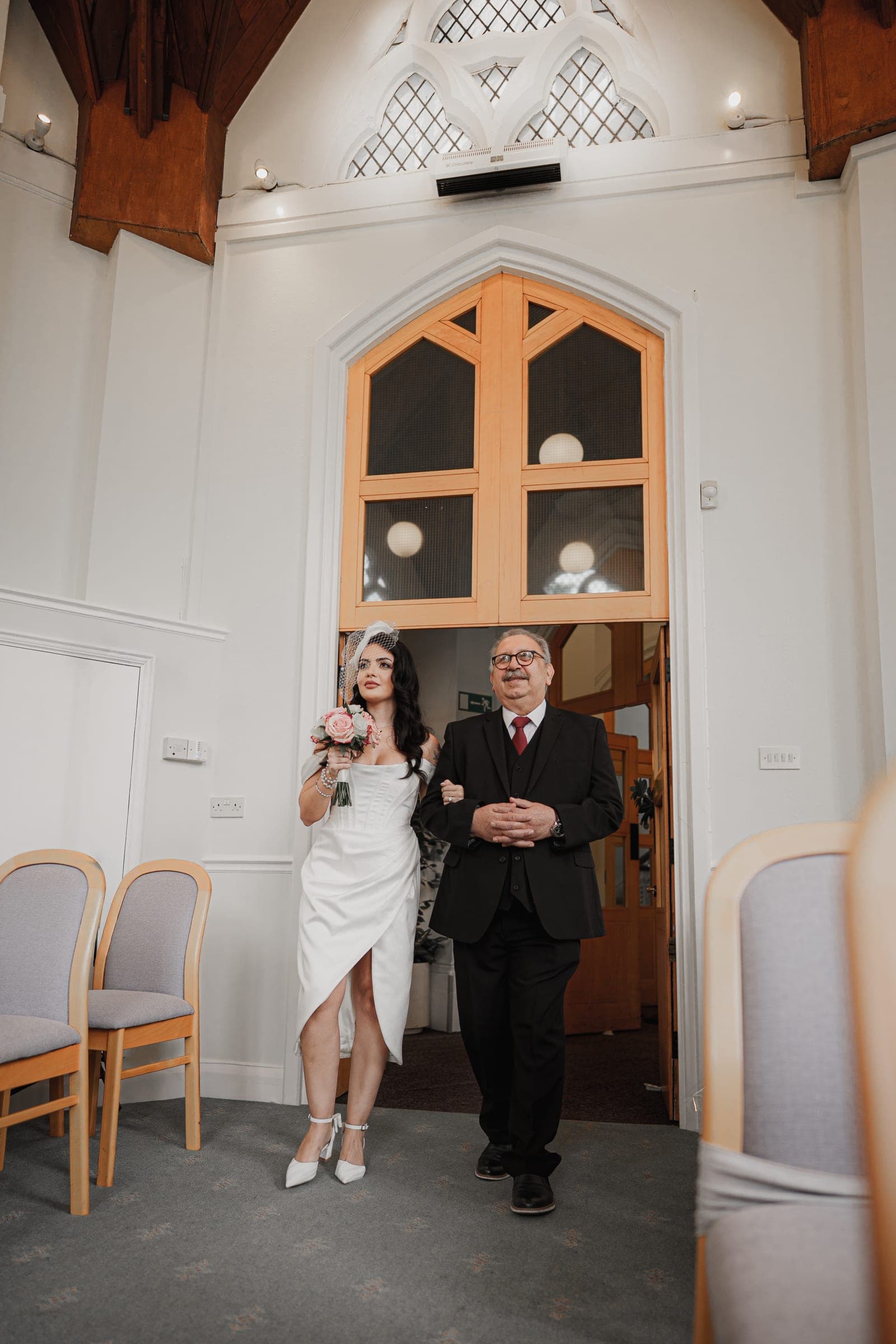 A bride entering the beamed ceremony room at Cheshunt Register Office on her father’s arm