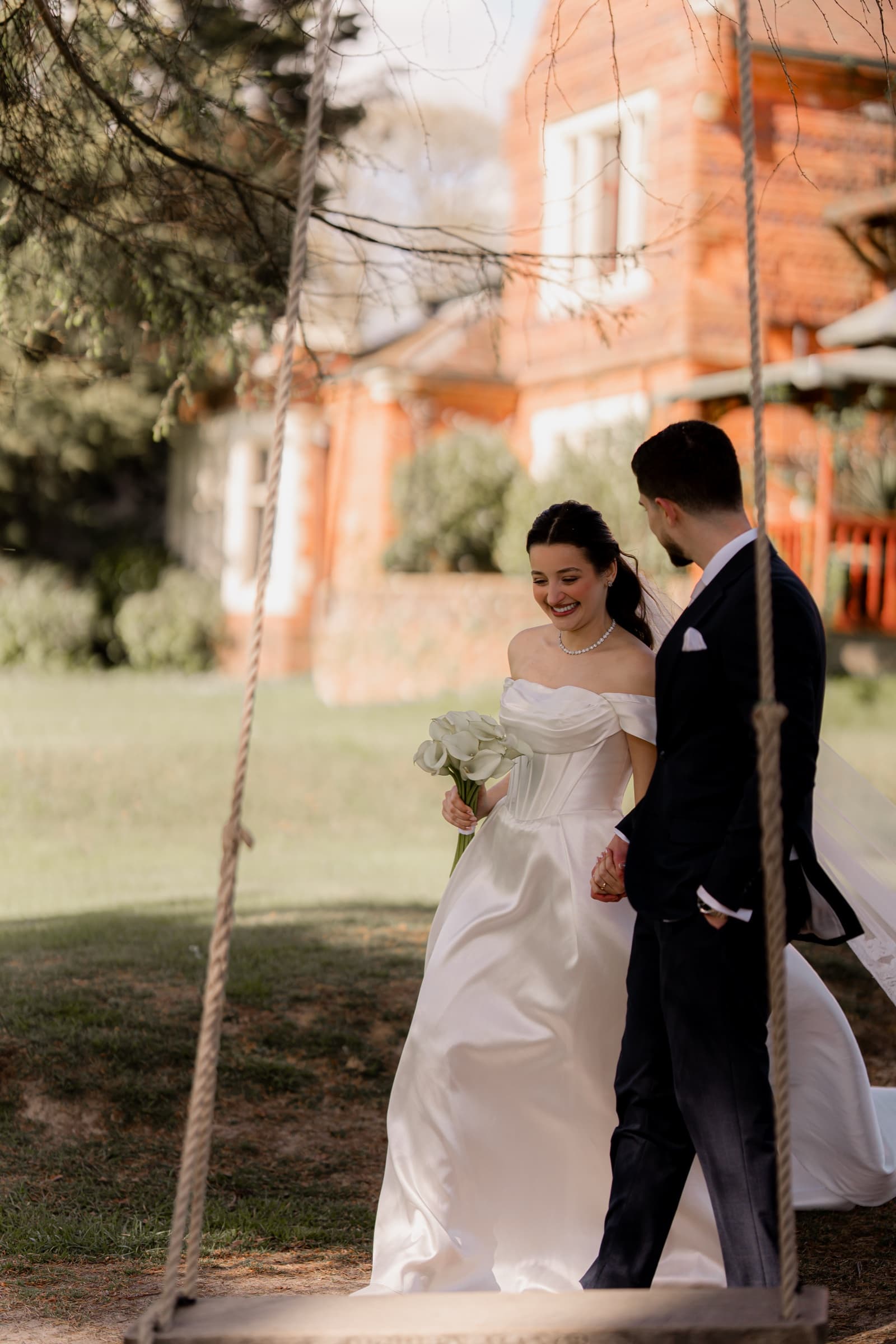 Newlyweds walking the lawn with the red-brick Highley Manor behind them