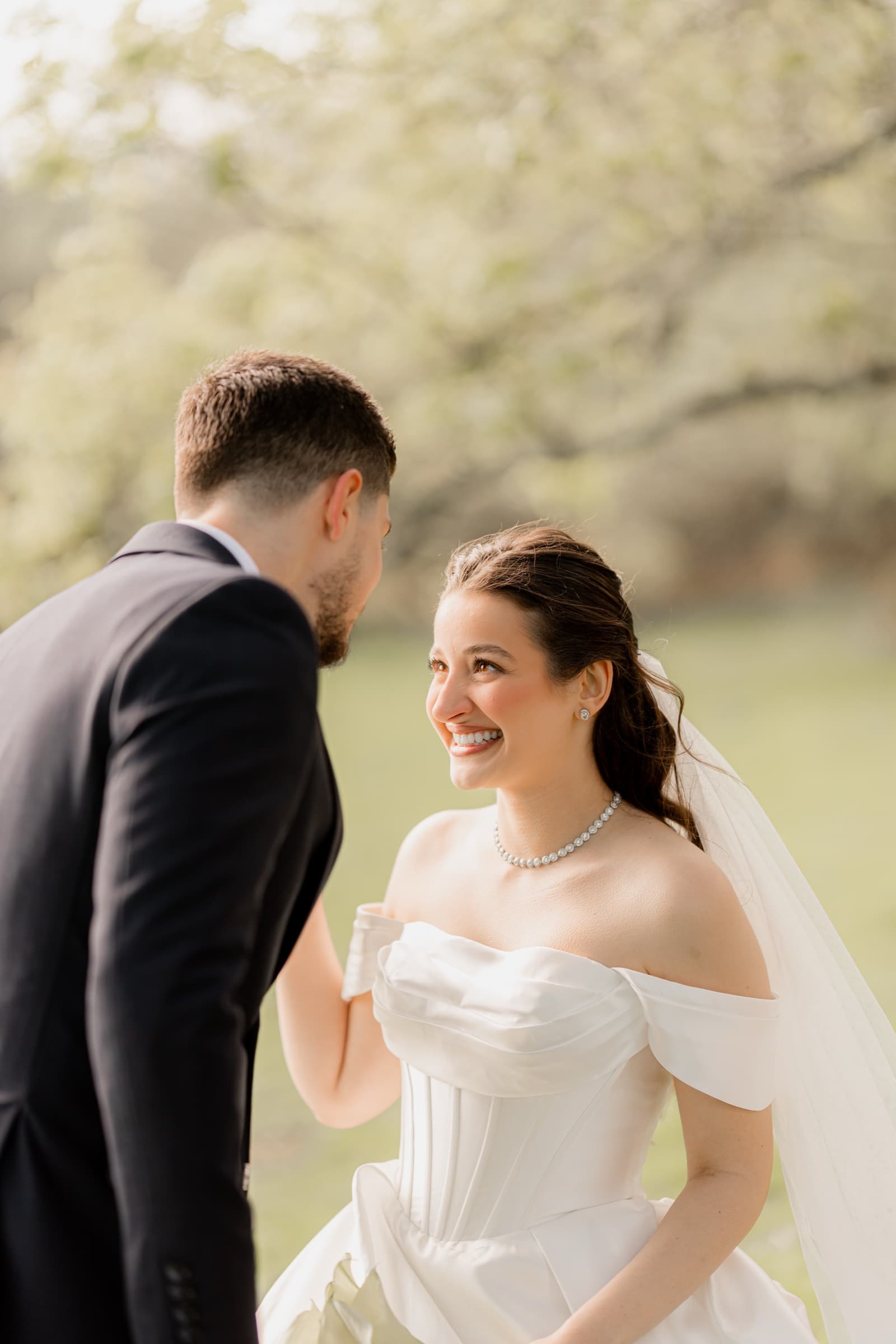 Bride laughing with her groom among spring blossom trees at Highley Manor