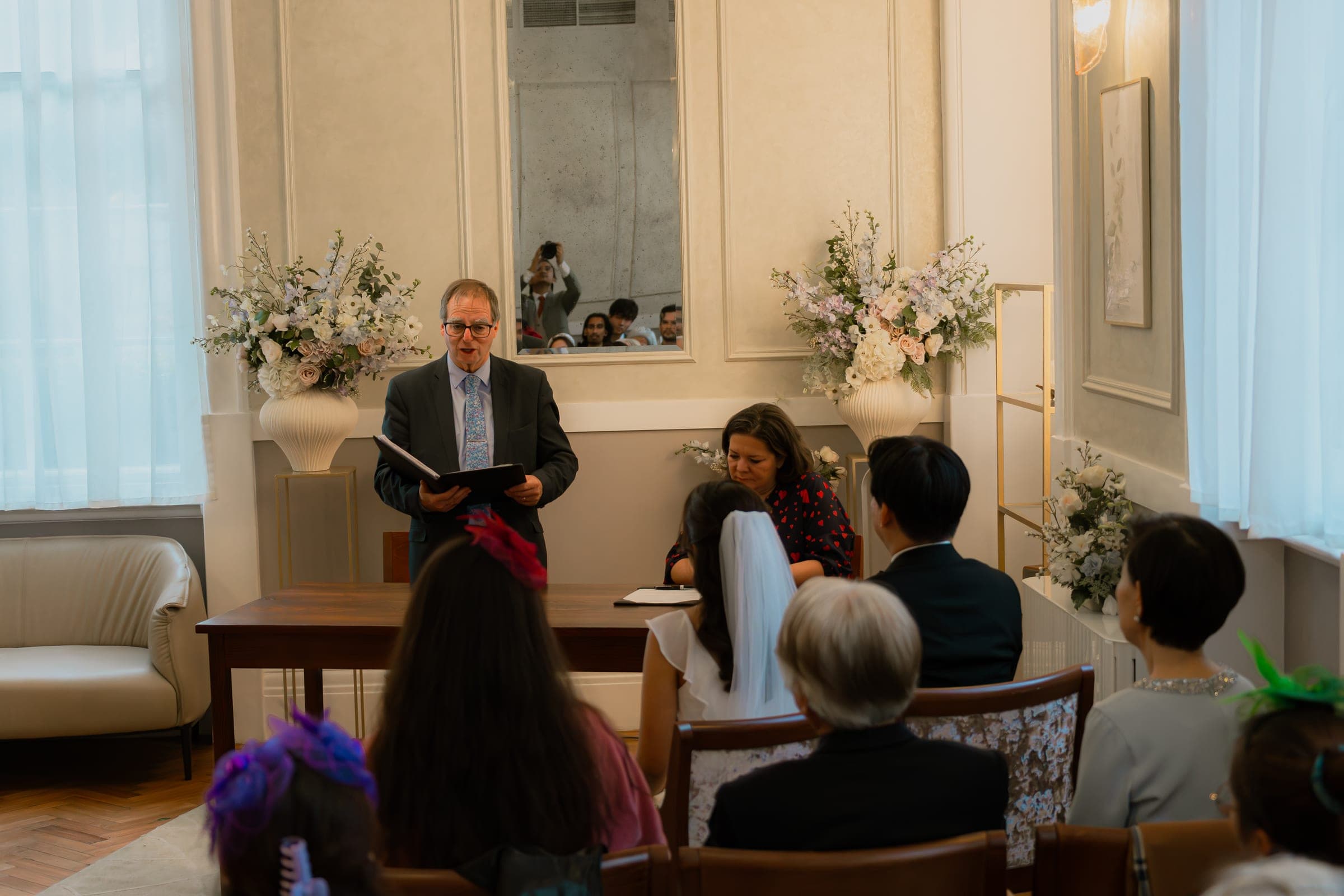 A registrar leading a wedding ceremony in a panelled London register office room, photographed by Evocation Photography