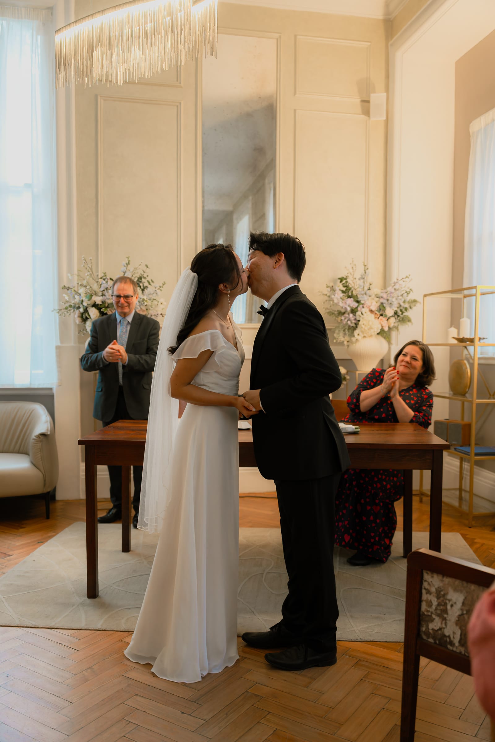 A couple’s first kiss as their witnesses applaud at a London register office wedding