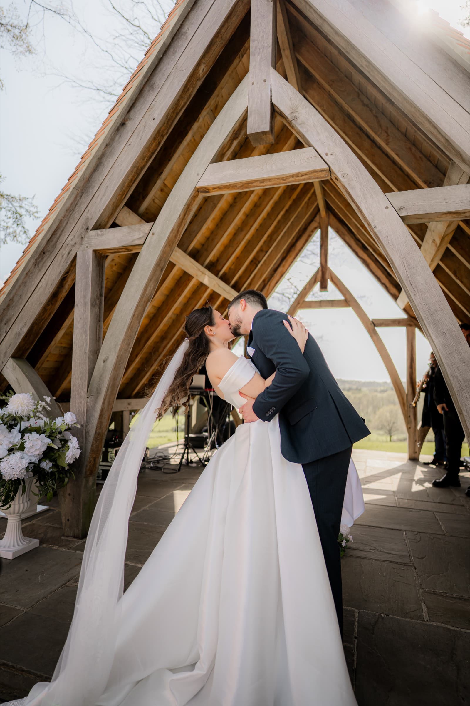 A couple kissing at the altar of a timber-framed ceremony barn