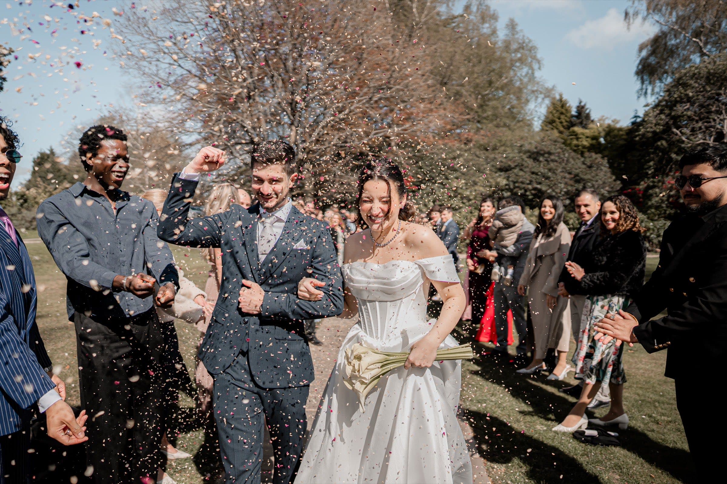 Guests throwing confetti over a couple as they walk through