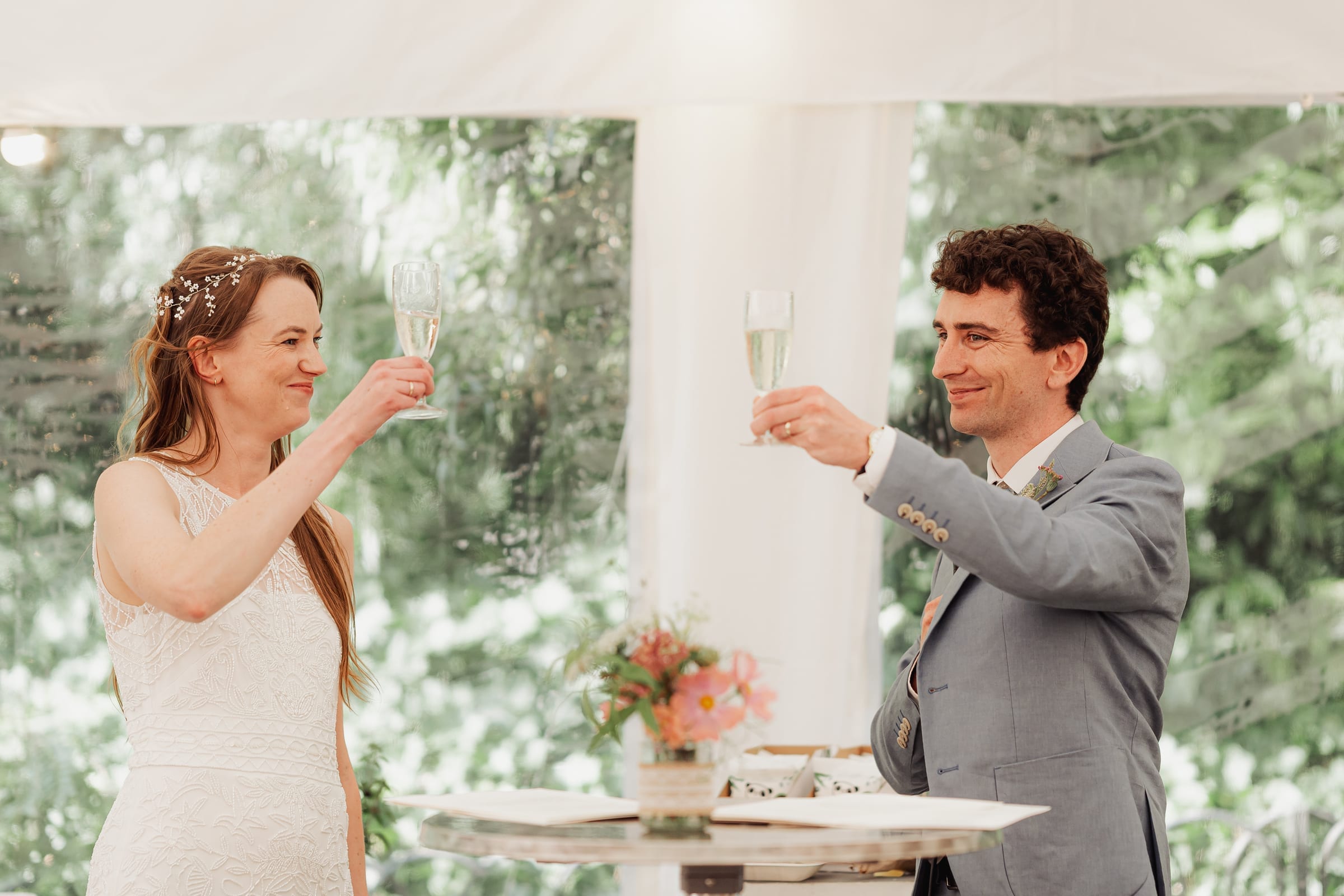 A couple raising a toast in a garden marquee at their summer wedding