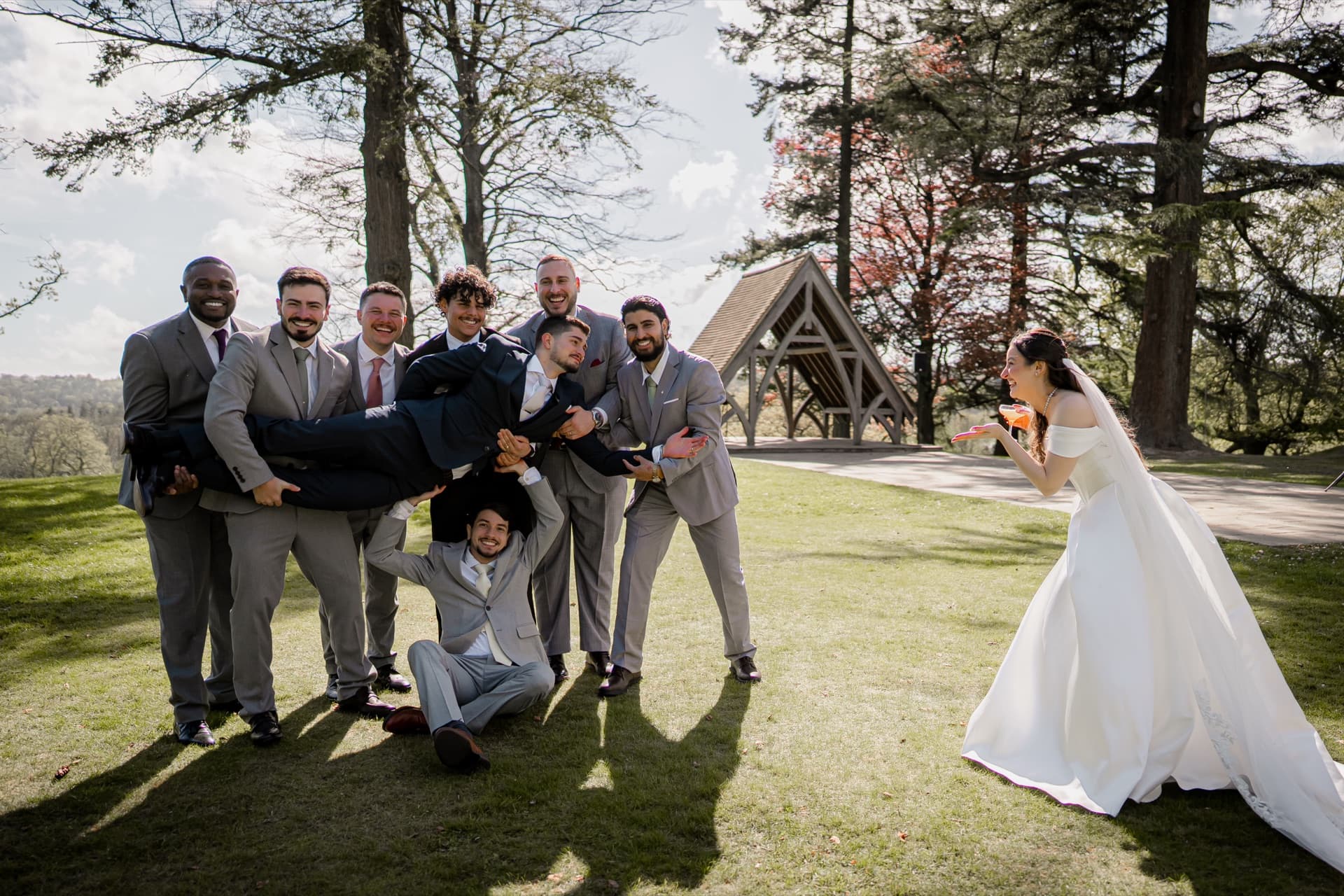 Groomsmen carrying the groom while the bride blows a kiss, relaxed documentary wedding photography in London